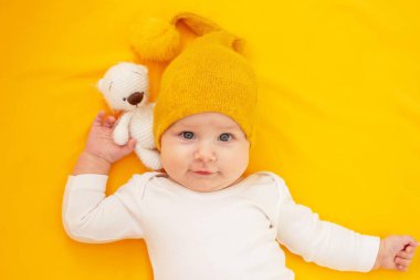 Sarı arka planda yatan gülümseyen bebek. Bebeğim.