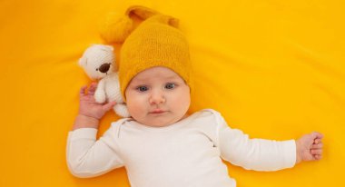 Sarı arka planda yatan gülümseyen bebek. Bebeğim.