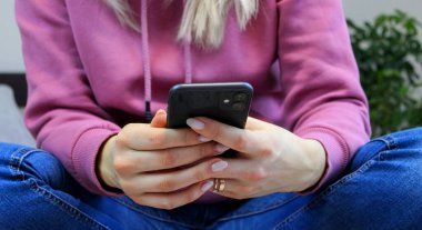 Kız yatakta akıllı telefon ekranına bakıyor. Seçici odak.