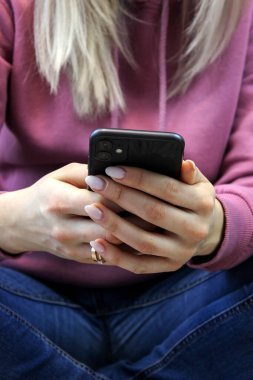 Kız yatakta akıllı telefon ekranına bakıyor. Seçici odak.