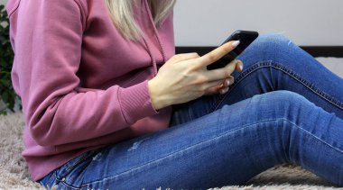 Kız yatakta akıllı telefon ekranına bakıyor. Seçici odak.