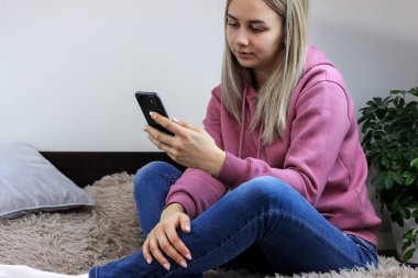 Kız yatakta akıllı telefon ekranına bakıyor. Seçici odak.