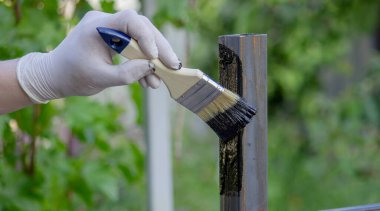 Bir adam metali siyah boyayla fırçayla boyuyor. Seçici odak.