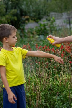 Anne çocuğun vücuduna sprey sprey sıkar. Seçici odak.