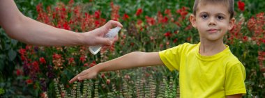 Anne çocuğun vücuduna sprey sprey sıkar. Seçici odak.