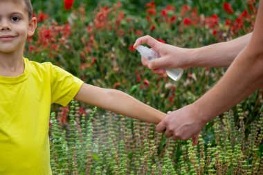 Anne çocuğun vücuduna sprey sprey sıkar. Seçici odak.