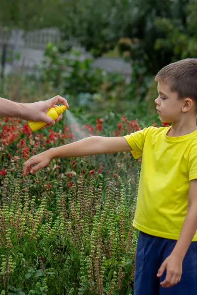 Anne çocuğun vücuduna sprey sprey sıkar. Seçici odak.