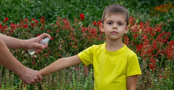 Anne çocuğun vücuduna sprey sprey sıkar. Seçici odak.
