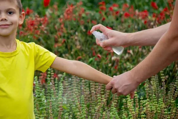 Anne çocuğun vücuduna sprey sprey sıkar. Seçici odak.