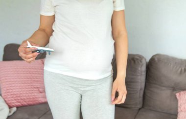 Hamile bir kadın uçakla oynuyor. Seçici odaklanma. Oyuncak.