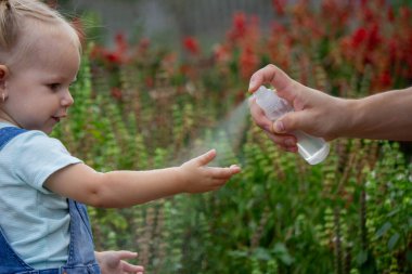 Anne çocuğun vücuduna sprey sprey sıkar. Seçici odak.