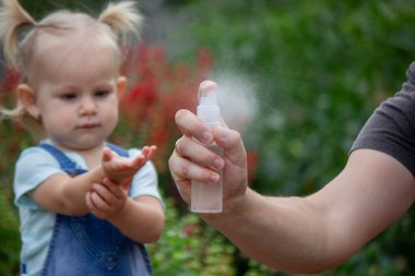 Anne çocuğun vücuduna sprey sprey sıkar. Seçici odak.