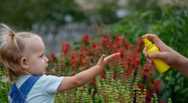 Anne çocuğun vücuduna sprey sprey sıkar. Seçici odak.