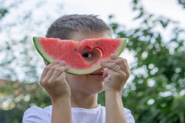 Bahçede karpuz yiyen bir çocuk. Seçici odak.