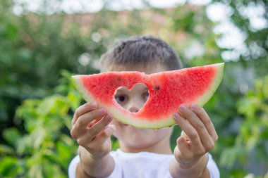 Bahçede karpuz yiyen bir çocuk. Seçici odak.