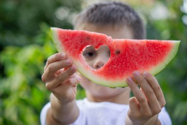 Bahçede karpuz yiyen bir çocuk. Seçici odak.