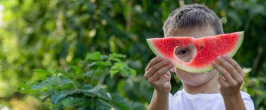 Bahçede karpuz yiyen bir çocuk. Seçici odak.