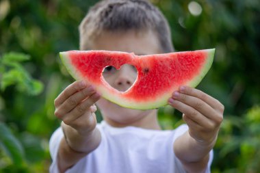 Bahçede karpuz yiyen bir çocuk. Seçici odak.