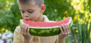 Bahçede karpuz yiyen bir çocuk. Seçici odak.