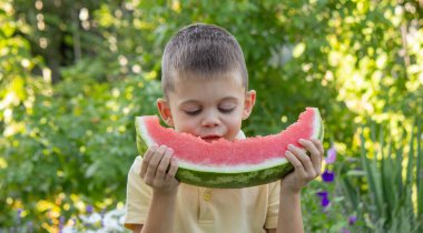 Bahçede karpuz yiyen bir çocuk. Seçici odak.