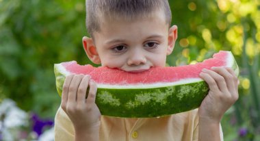 Bahçede karpuz yiyen bir çocuk. Seçici odak.