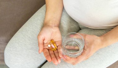 Hamile bir kadın vitamin ve takviyeler içer. Seçici odaklanma. Beyaz.