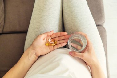 Hamile bir kadın vitamin ve takviyeler içer. Seçici odaklanma. Beyaz.