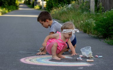 Çocuk asfalta tebeşirle çizer. Seçici odaklanma. Çocuk.