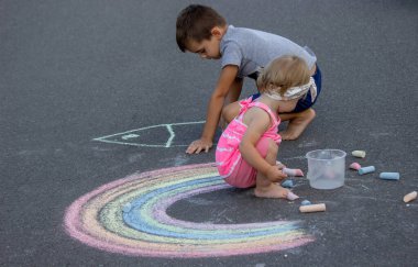 Çocuk asfalta tebeşirle çizer. Seçici odaklanma. Çocuk.