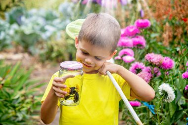 Çocuk bahçede bir kelebek yakalar.