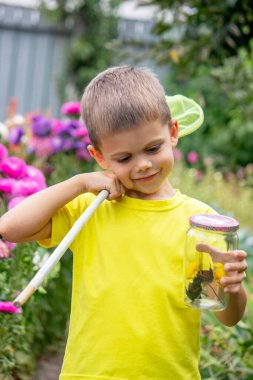 Çocuk bahçede bir kelebek yakalar.