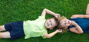 Çocuk yeşil çimlerin üzerinde yatıyor. Çocuk kameraya bakıyor.