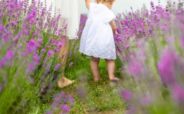 Anne ve çocuğun bacakları çimenlerde koşuyor..