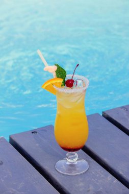 Havuz kenarında güzel bir kokteyl, şapka ve güneş gözlüğü..