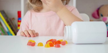 Şeker ya da vitamin yiyen küçük bir kız. Çocuk