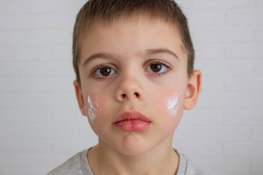 Çocuk kuru cilt için yüzüne krem sürüyor.