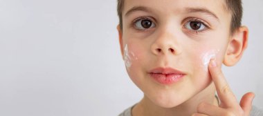 Çocuk kuru cilt için yüzüne krem sürüyor.