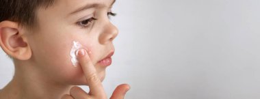 Çocuk kuru cilt için yüzüne krem sürüyor.