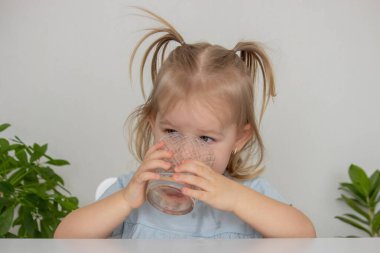 Küçük kız bardaktan su içiyor. Seçici odak.