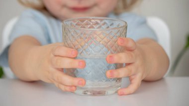 Küçük kız bardaktan su içiyor. Seçici odak.