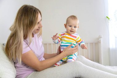 Anne yatakta bebekle oynuyor, bebeğe sarılıyor. Mutlu çocukluk.