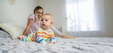 Yavrusu yanındaki yatakta sürünürken genç bir anne telefonuna bakar.