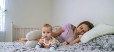 Genç anne uyuyor ve bebek onun yanında yürüyor. Yorgun anne.