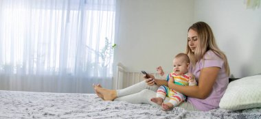 Yavrusu yanındaki yatakta sürünürken genç bir anne telefonuna bakar..