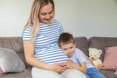 Hamile bir kadın en büyük oğluna sarılır. Seçici odaklanma. Aşk.