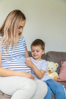 Hamile bir kadın en büyük oğluna sarılır. Seçici odaklanma. Aşk.