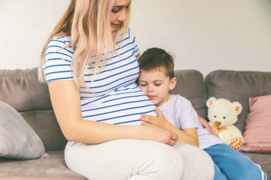 Hamile bir kadın en büyük oğluna sarılır. Seçici odaklanma. Aşk.