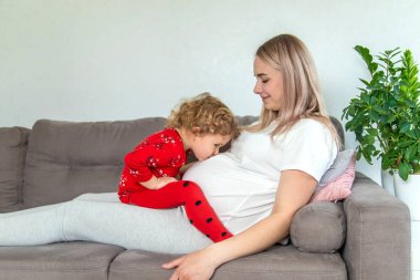 Hamile bir kadın en büyük kızına sarılır. Seçici odaklanma. Aşk.