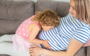 Hamile bir kadın en büyük kızına sarılır. Seçici odaklanma. Aşk.