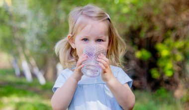 Küçük kız bardaktan su içiyor..